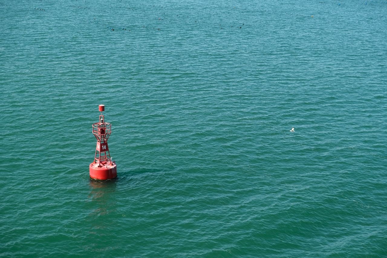 Crafting Captivating Headlines: Your awesome post title goes here A red navigational buoy floating in calm blue ocean water under clear skies.