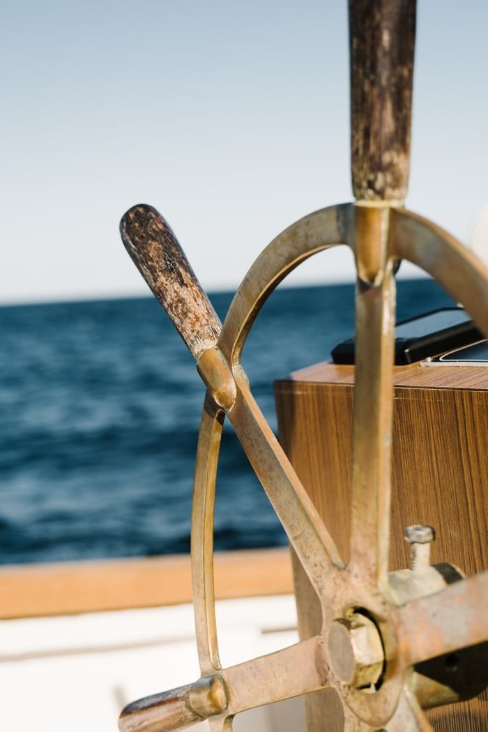 About Close-up view of a vintage ship's wheel with a scenic ocean backdrop, showcasing nautical charm.